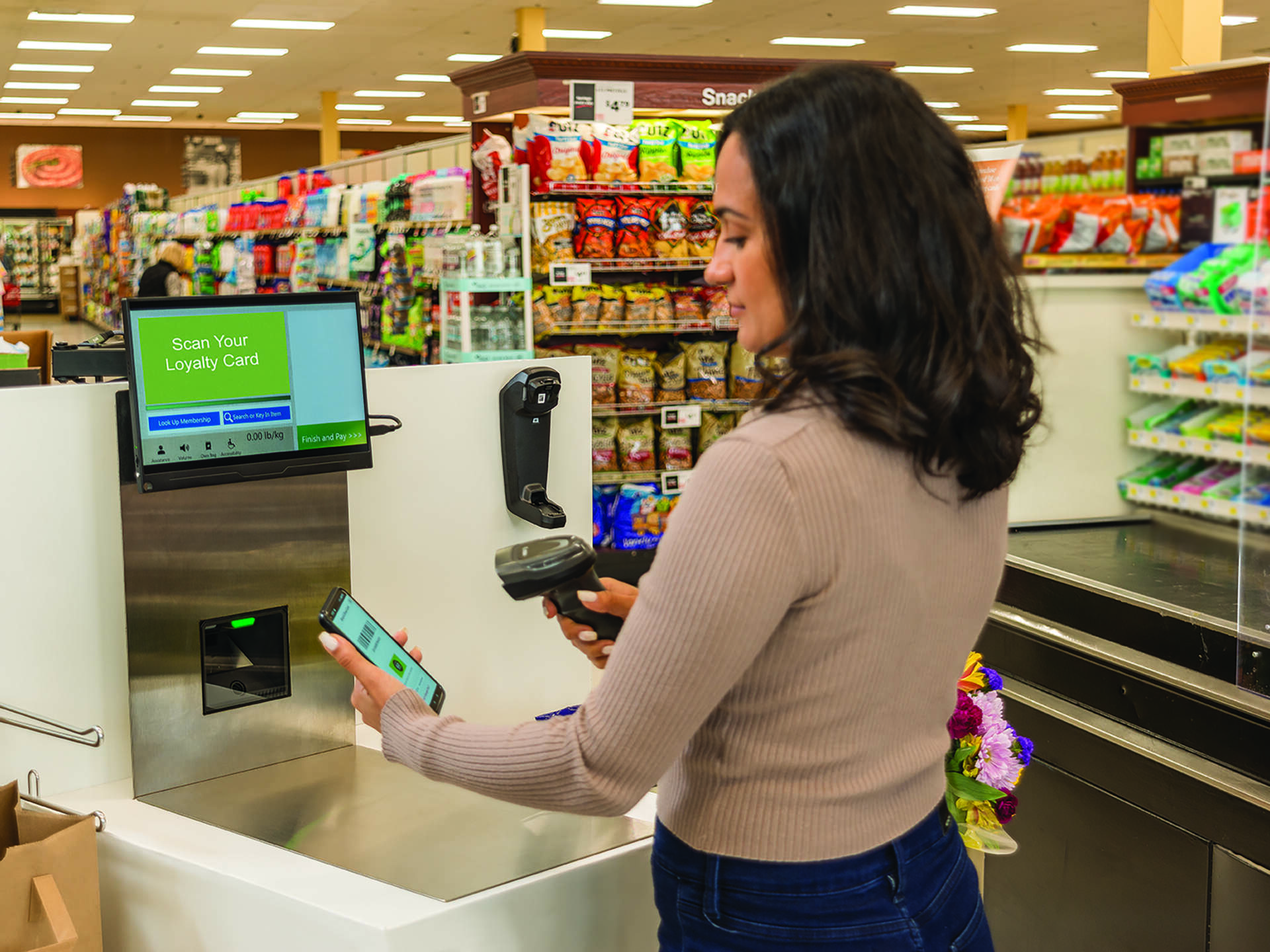Retail customer presenting a phone loyalty barcode to a checkout scanner